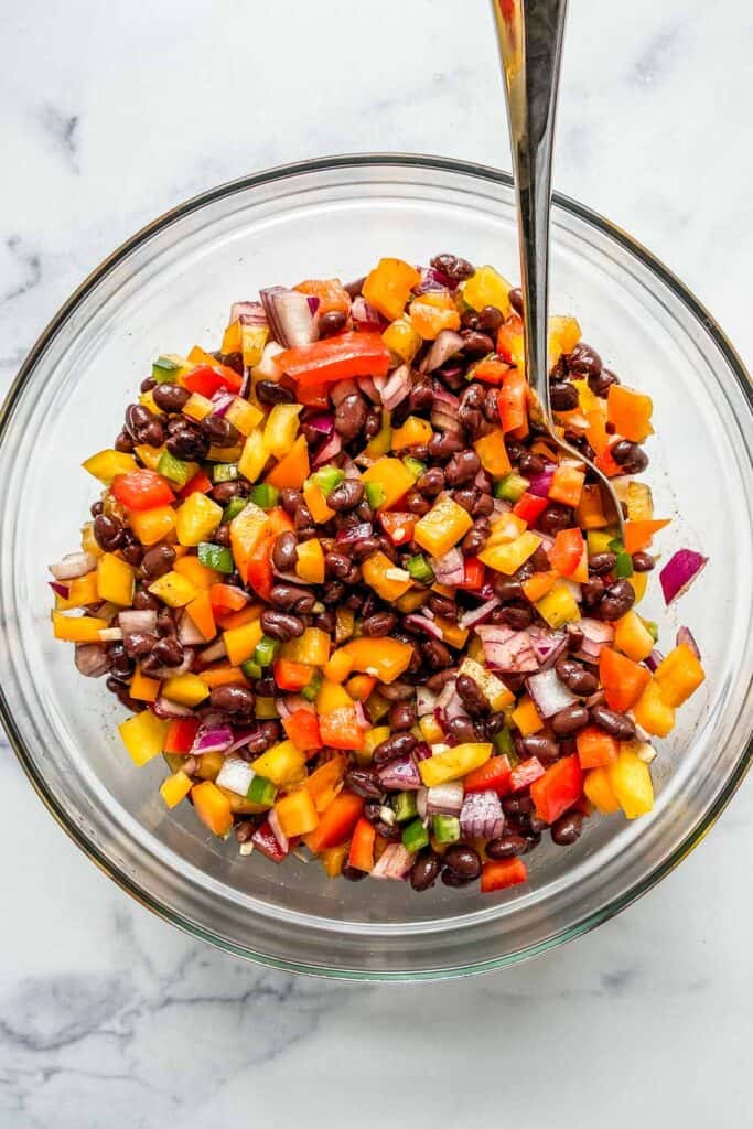 black bean salad in a glass serving bowl with a spoon