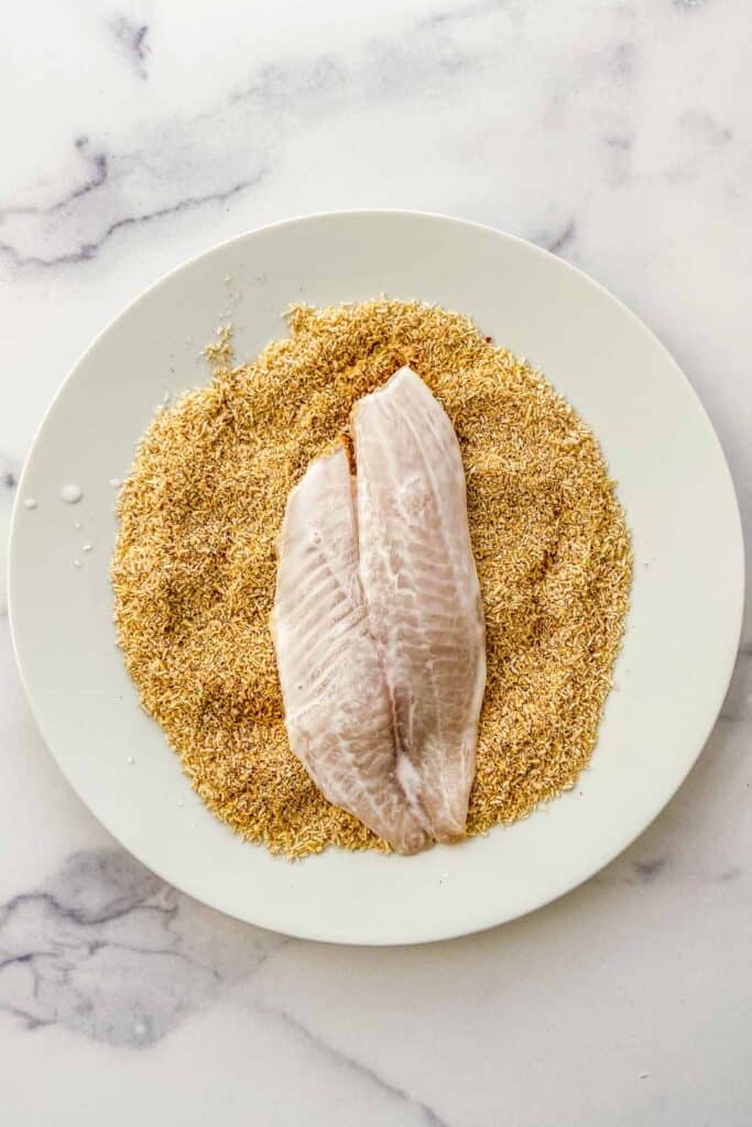 tilapia being dredged in coconut flakes and spices