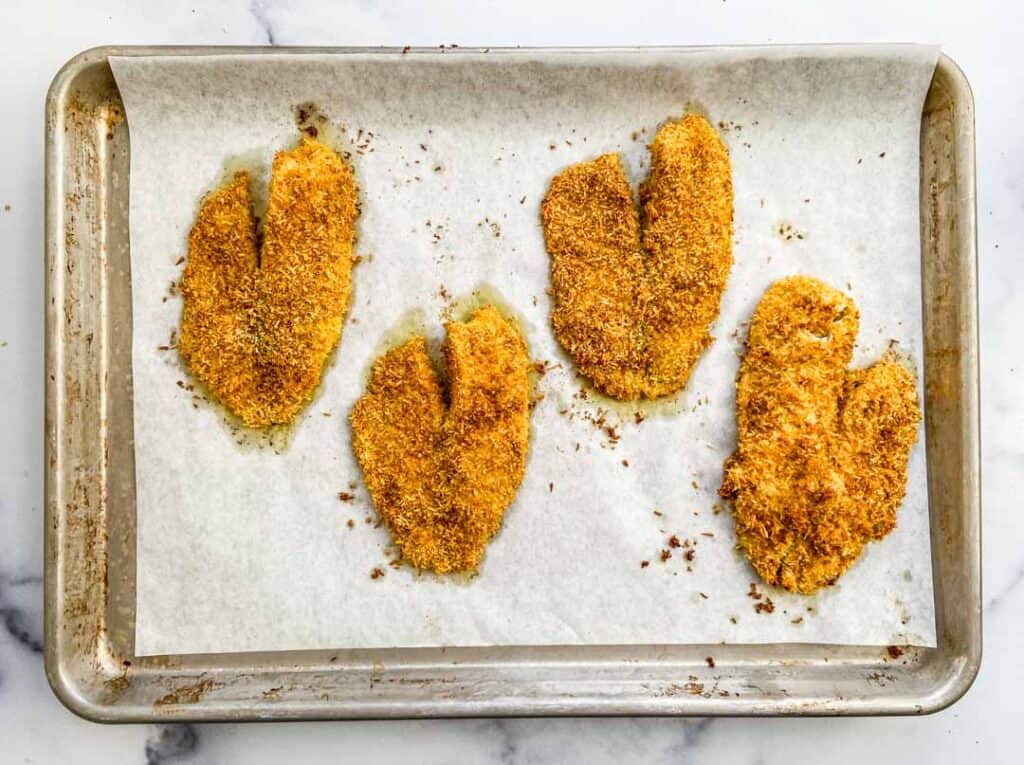 coconut crusted tilapia on a baking sheet