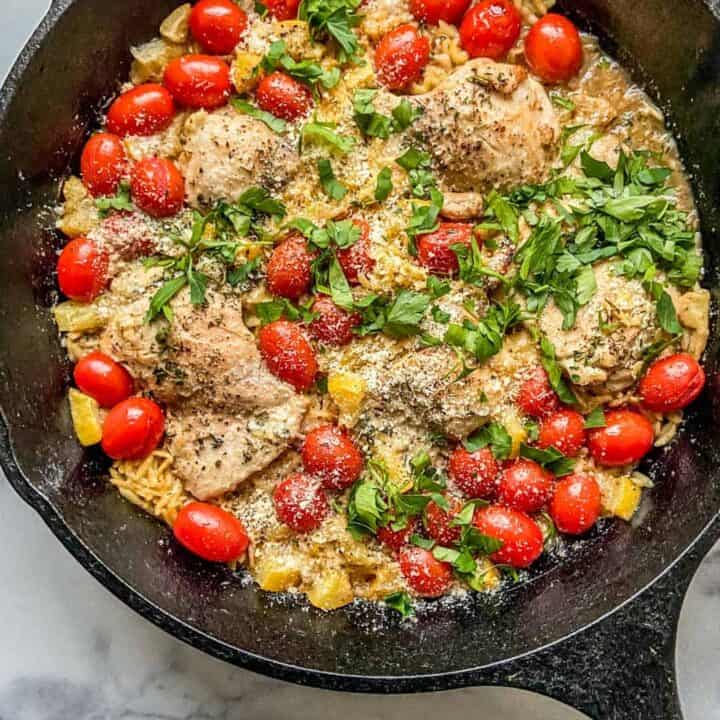 chicken with orzo and lemons in a cast iron skillet.