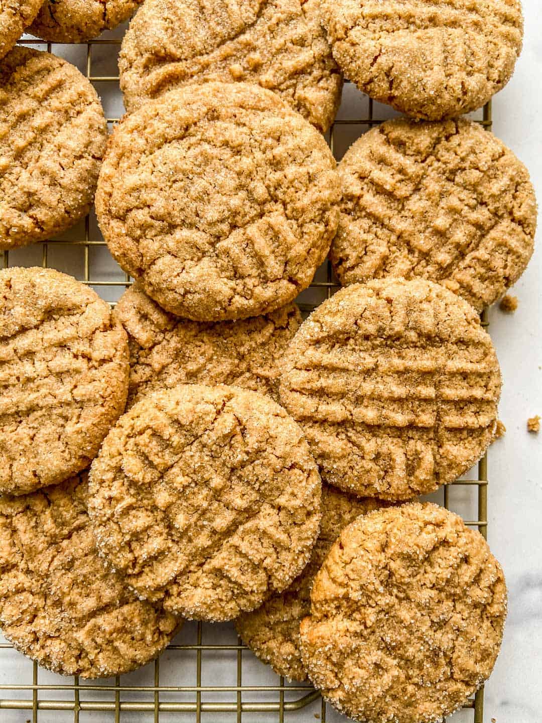 Vegan peanut butter cookies stacked together on a cooling rack.