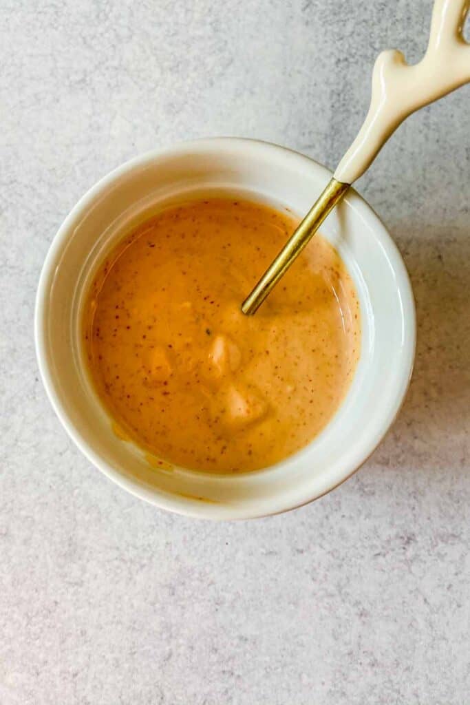 A small bowl of spicy mayo sauce with a spoon.