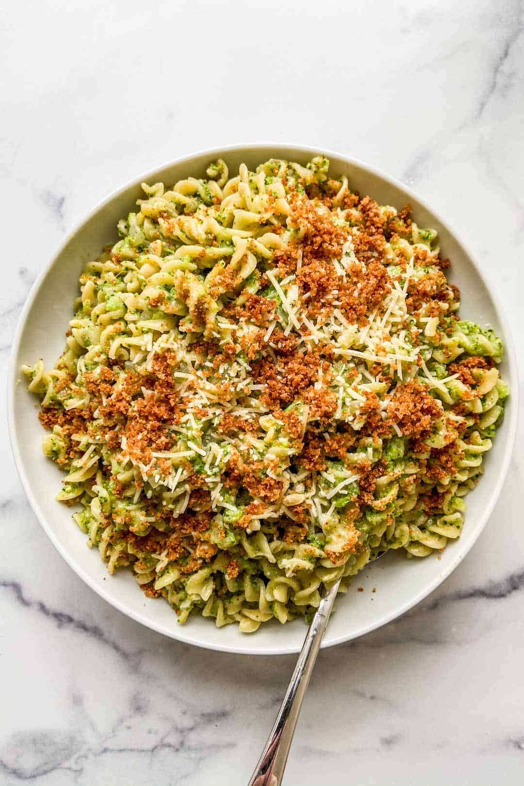 Broccoli pasta in a large serving bowl with a spoon.