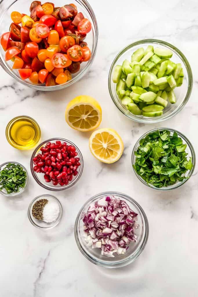 Middle Eastern salad ingredients in small bowls on a marble background.