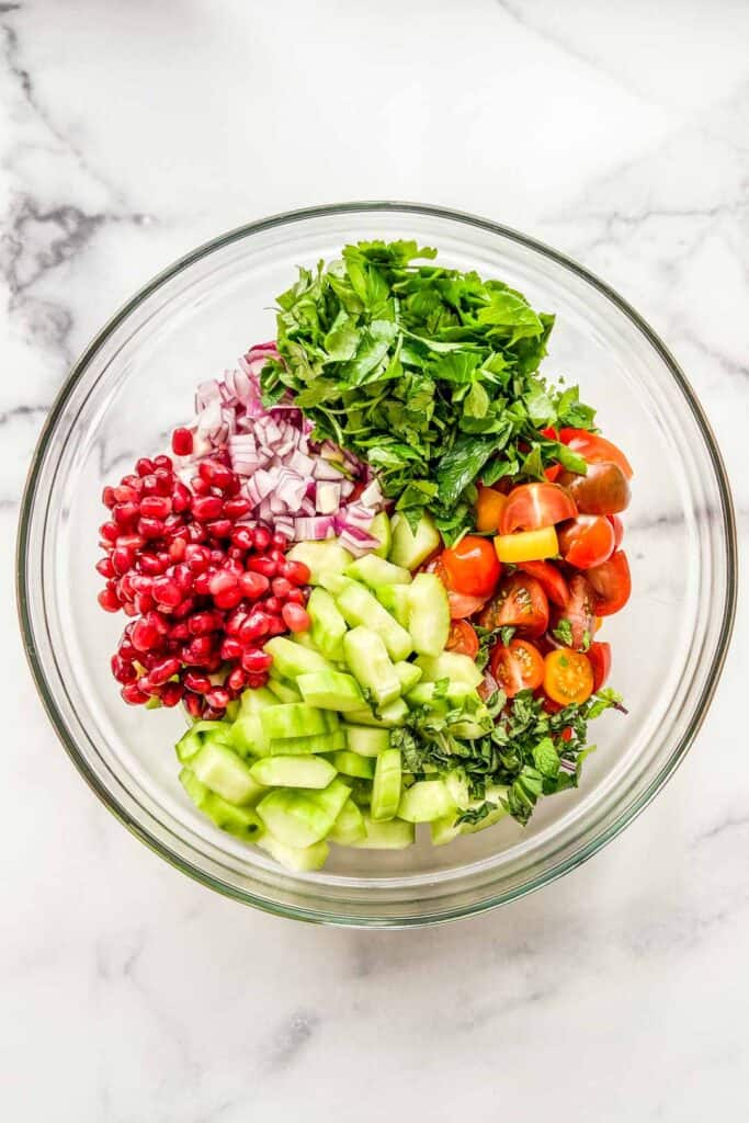 Ingredients for a cucumber tomato chopped salad in a mixing bowl.