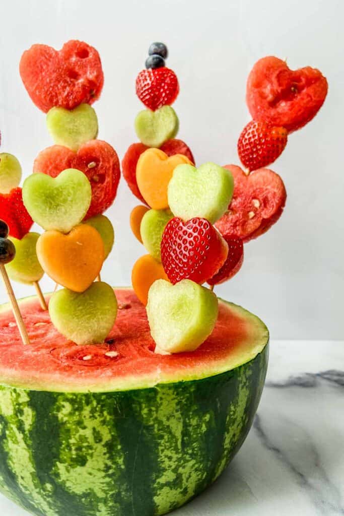 Valentine's day fruit skewers stuck in a half watermelon.