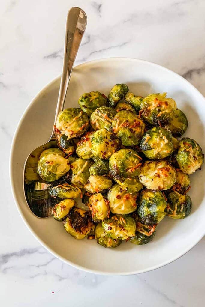 Smashed Brussels sprouts in a serving bowl with a large spoon.