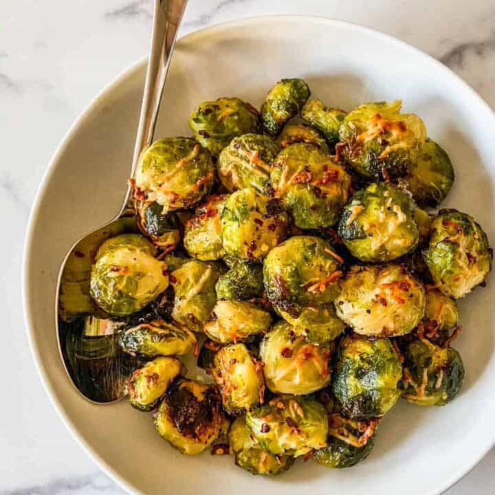 Smashed Brussels sprouts in a serving bowl with a large spoon.