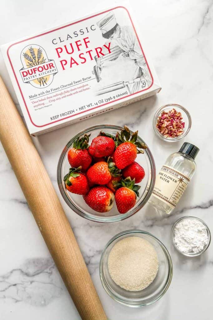 Ingredients for strawberry tartlets alongside a rolling pin.