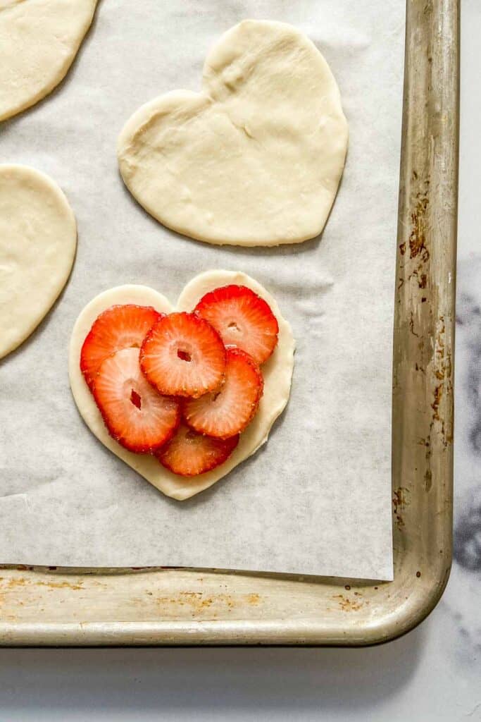 Strawberries on puff pastry hearts before going in the oven.