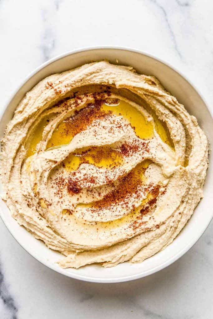 A closeup shot of a bowl of hummus with olive oil and sumac.