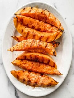 Grilled cantaloupe on a white serving plate.