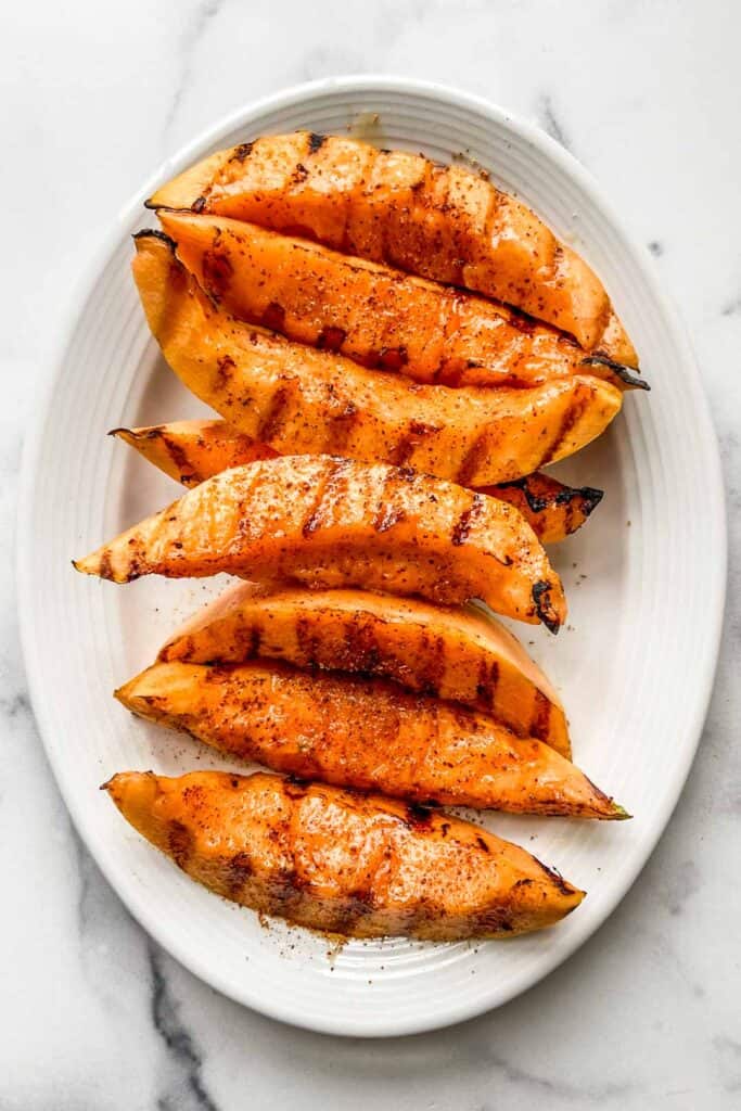 Grilled cantaloupe on a white serving plate.