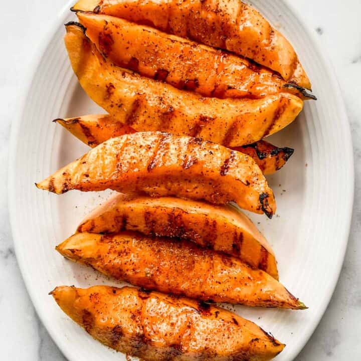 Grilled cantaloupe on a white serving plate.