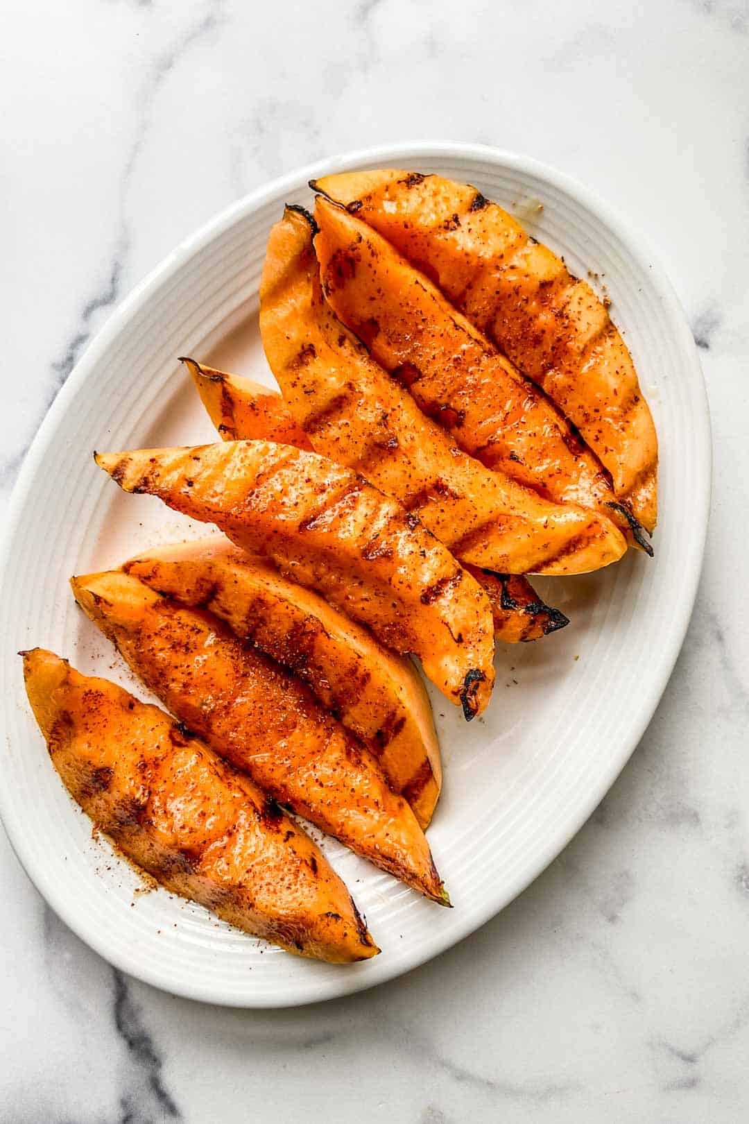 A serving plate with slices of grilled cantaloupe.