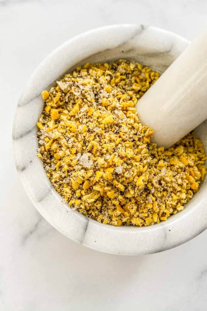 An overhead shot of a mortar and pestle with lemon pepper seasoning. 