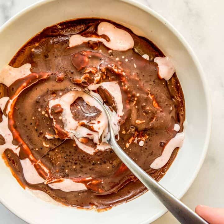 An overhead shot of a magic shell smoothie bowl with a silver spoon.