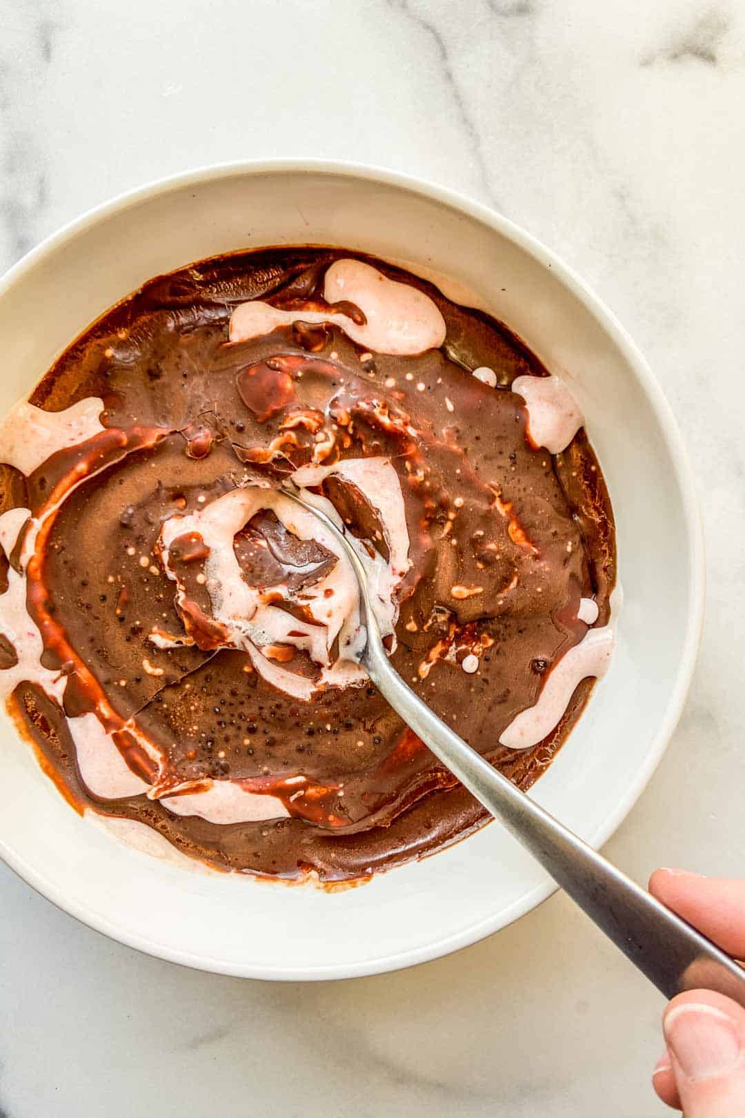 An overhead shot of a magic shell smoothie bowl with a silver spoon.