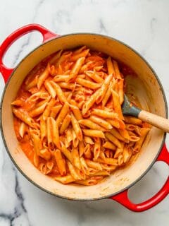 An overhead shot of a dutch oven full of roasted red pepper penne pasta.