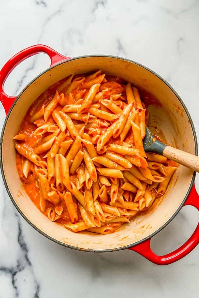 An overhead shot of a dutch oven full of roasted red pepper penne pasta.