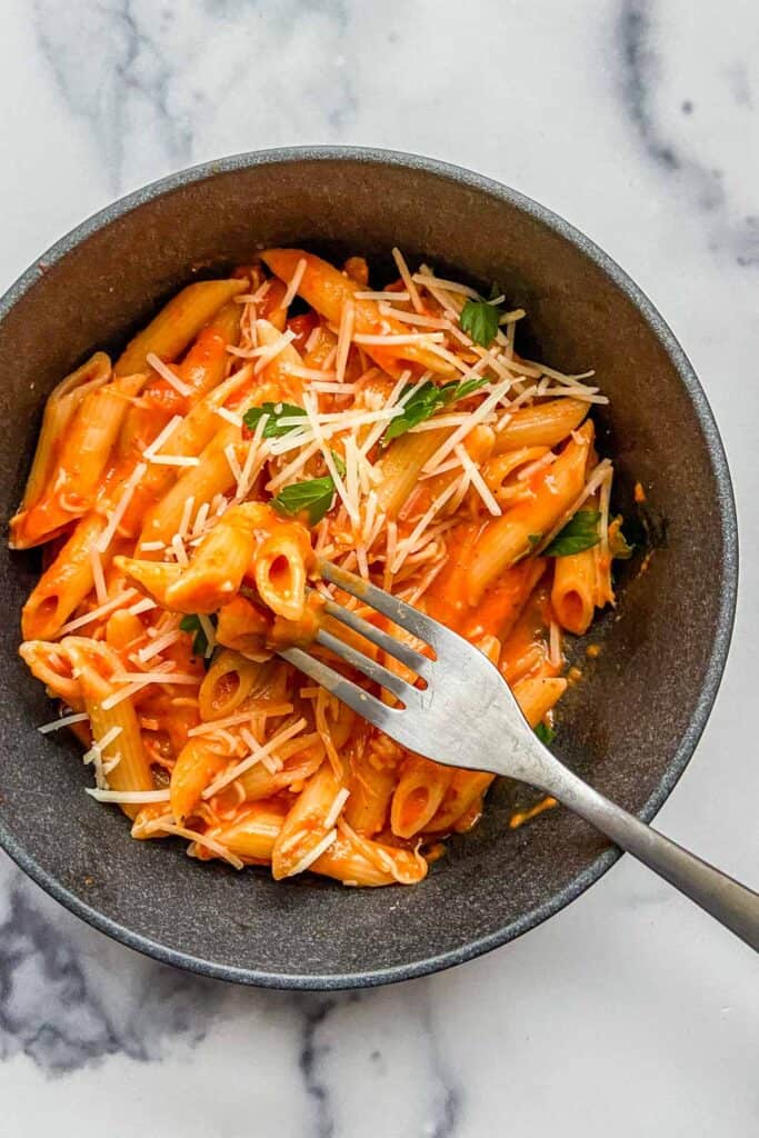 A bowl of roasted red pepper pasta with a fork.