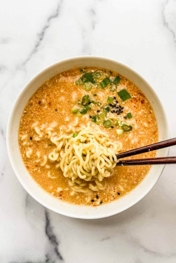 An overhead shot of a bowl of ramen with chopsticks pulling out some noodles.