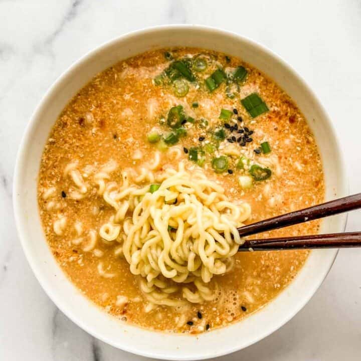 An overhead shot of a bowl of ramen with chopsticks pulling out some noodles.