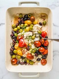 An overhead shot of a baking dish with feta, olives, and tomatoes.