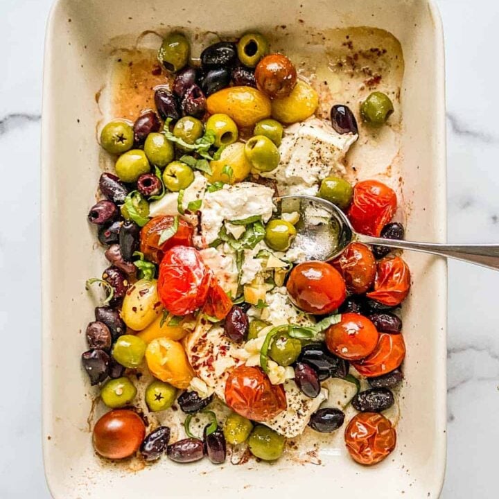 An overhead shot of a baking dish with feta, olives, and tomatoes.