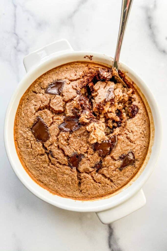 An overhead shot of a ramekin of chocolate baked oats with a spoon in it.