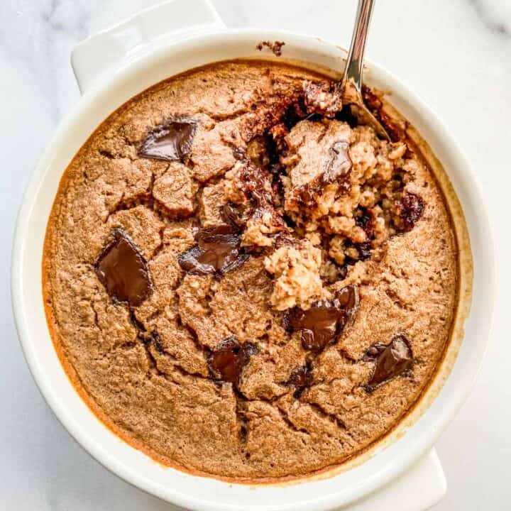 An overhead shot of a ramekin of chocolate baked oats with a spoon in it.