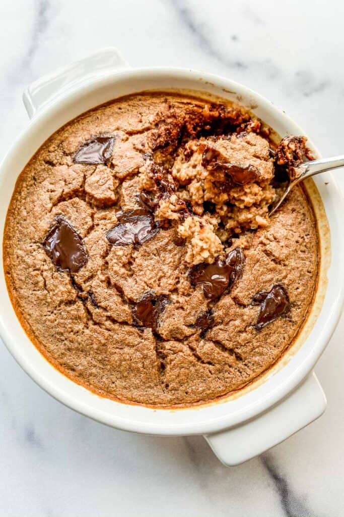 An overhead shot of a ramekin of chocolate baked oats with a spoon in it.