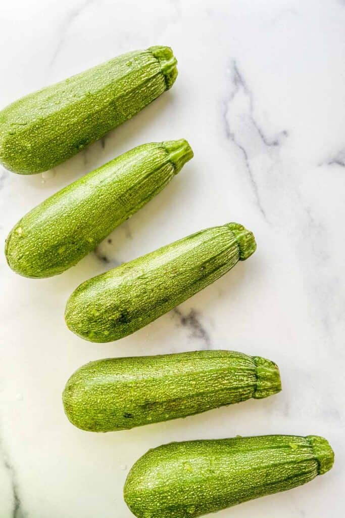 Several small marrow squash on a marble background.