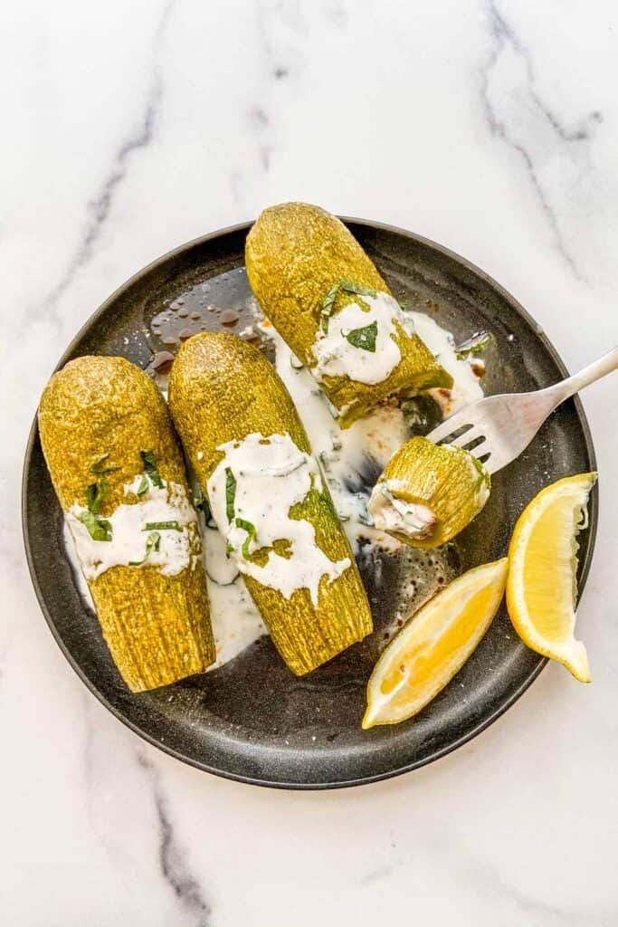 An overhead shot of stuffed zucchinis topped with yogurt.