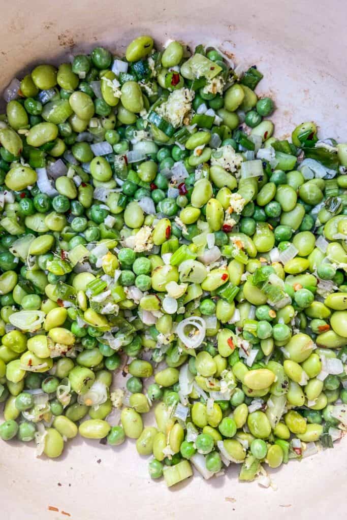 A closeup shot of the sautéed edamame, peas, shallots, and scallions.