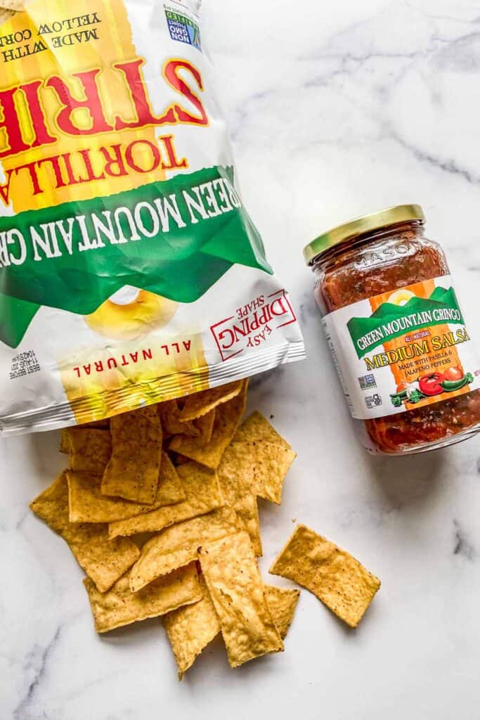 An open bag of tortilla strips and a can of salsa.
