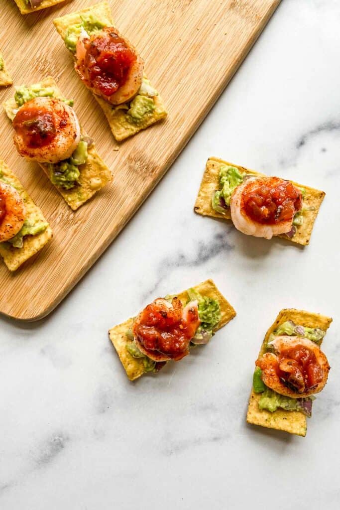 Grilled shrimp bites on a marble background and a bamboo cutting board.