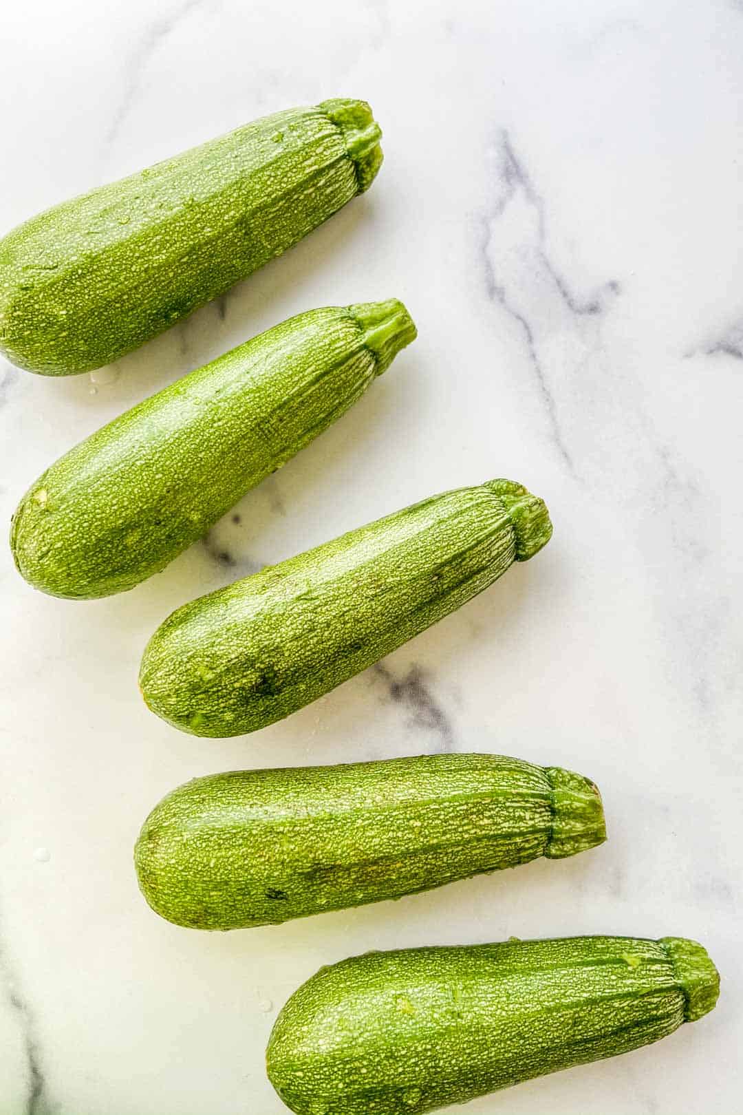 Small zucchini squash on a marble background.