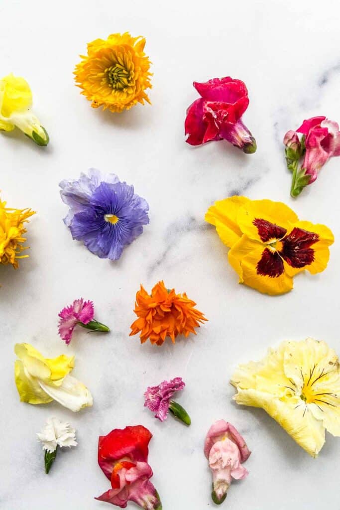 An assortment of edible flowers on a marble background.