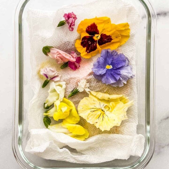 Edible flowers on a paper towel in a glass container.