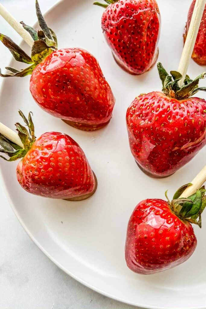 A closeup shot of tanghulu strawberries on a white plate.