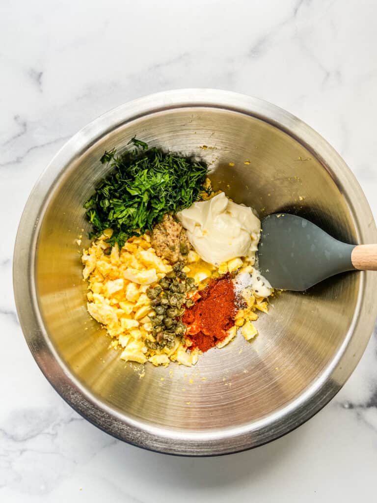 Egg salad ingredients in a metal mixing bowl.