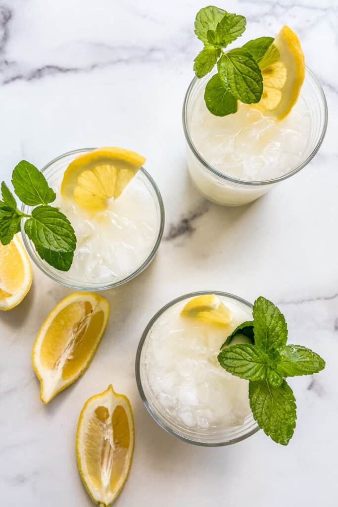 Three glasses of creamy lemonade topped with mint and sliced lemons.