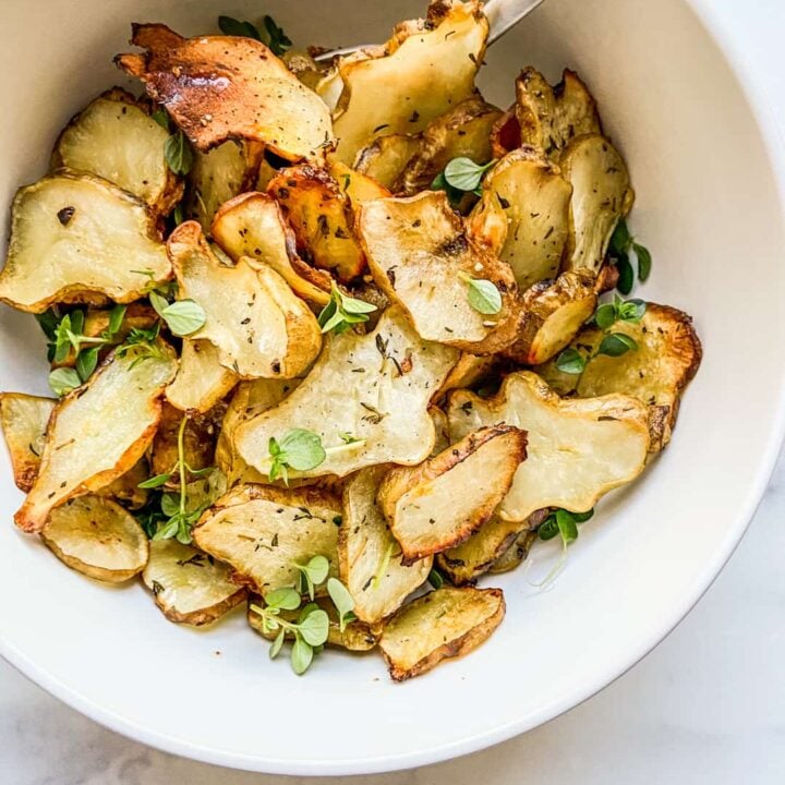 A bowl of roasted sunchokes with a silver spoon.