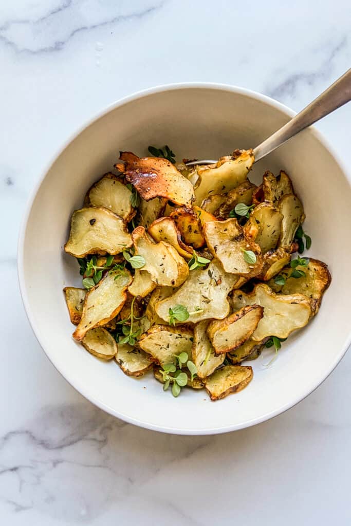 An overhead shot of a bowl of roasted Jerusalem artichokes. 