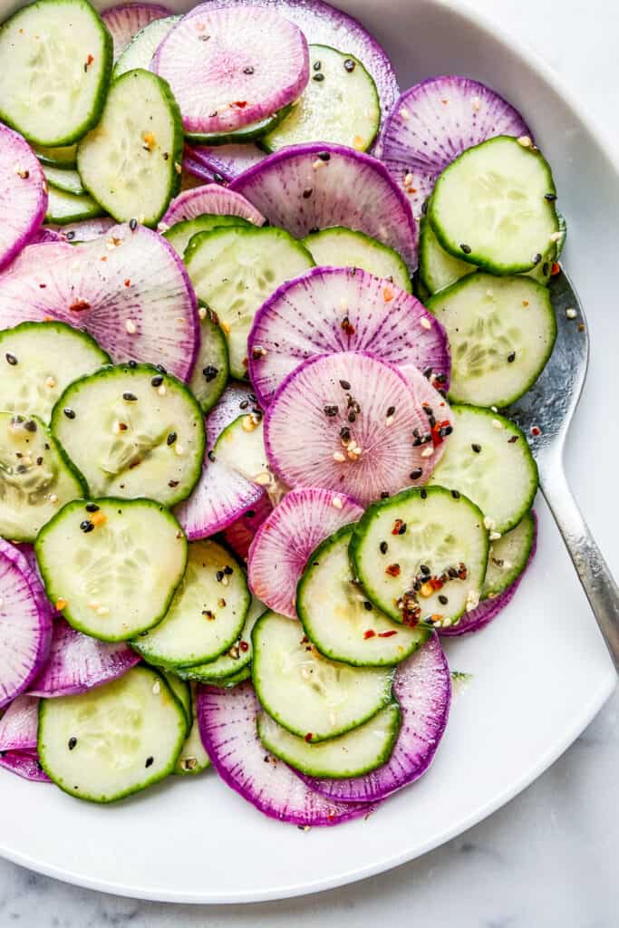 A closeup of a bowl of daikon radish salad with cucumbers.