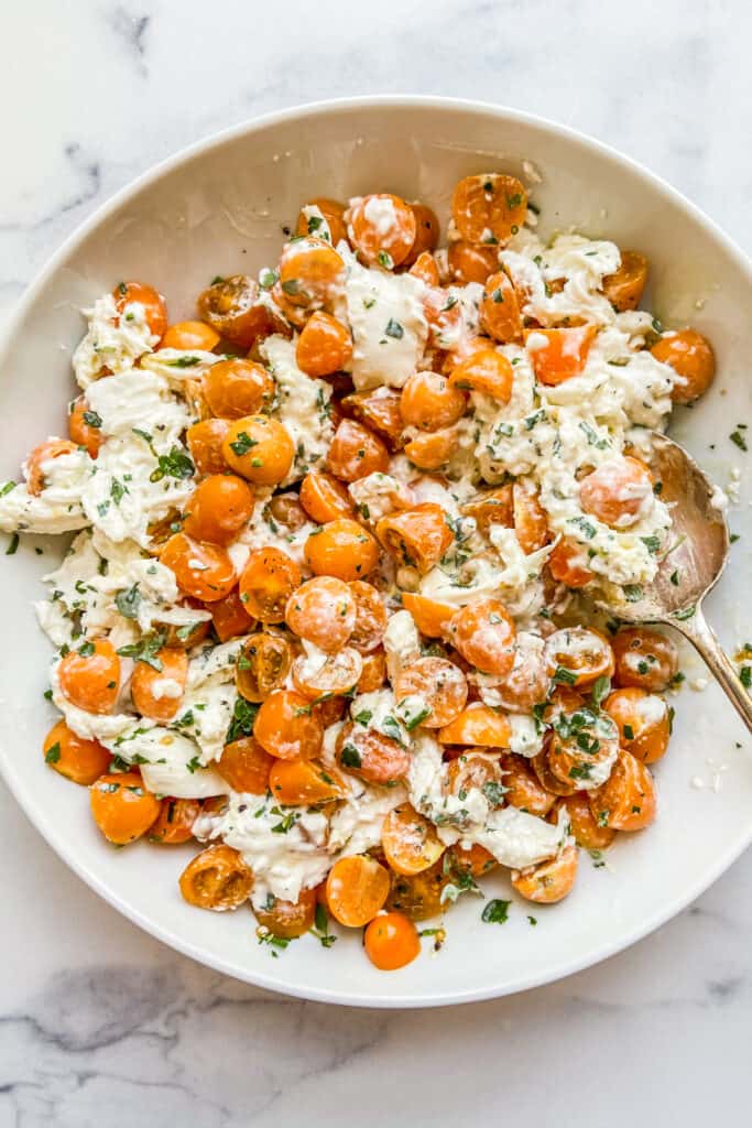 A bowl of shredded burrata, goldenberries, and tomatoes. 