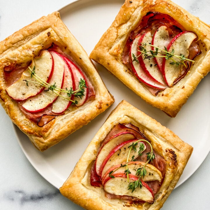 Three ham and cheese tarts on a white plate.