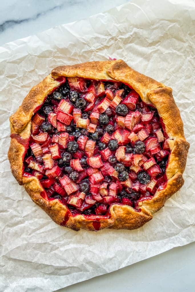 An overhead shot of a rhubarb blueberry galette right after it has come out of the oven.