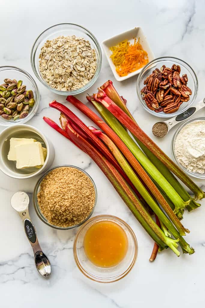 Ingredients for a rhubarb crumble on a marble backdrop.